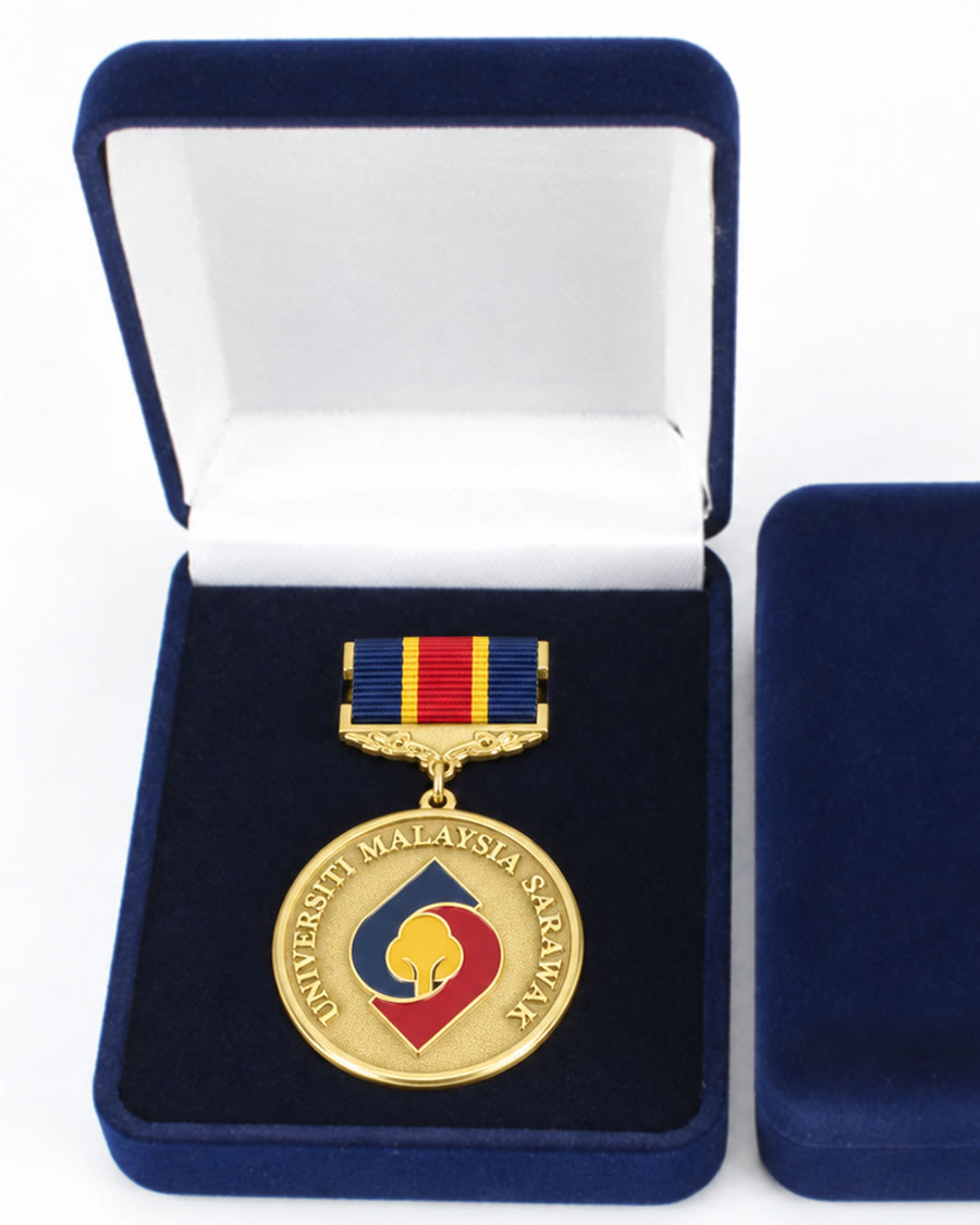 Gold UNIMAS medal with enamel crest on a navy and red ribbon in a velvet case