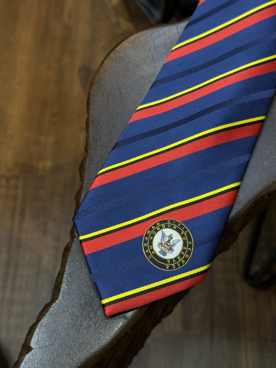 Close-up of a crest woven into a striped tie